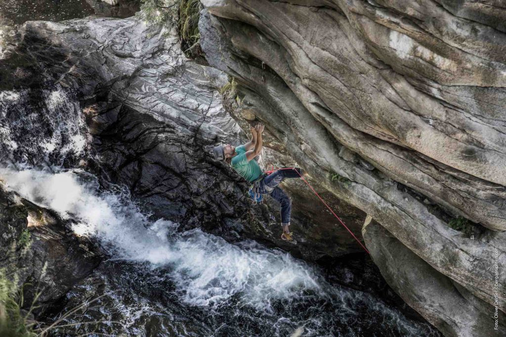 Das Bild zeigt einen Kletterer mit Hut über der Hochsteg Schlucht in der Mitte der Malteiner Wasserpiele. Unten in der Schlucht weiße Wasserwirbel, rundherum überall grauer Fels.