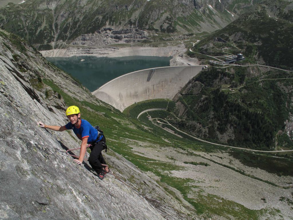 Das Bild zeigt einen Kletterer mit blauem Shirt in einer Granitplatte über der Kölnbreinsperre. Eines der gratis Topo der Langkar Routen ist von dieser Route!