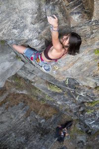 Das bild zeigt eine junge Klettererin im Klettergarten Danielsberg. Sie klettert hoch oben in der Wand, unter ihr unscharf die Felswand.
