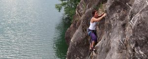 Eine Frau klettert im Klettergarten Jungfernsprung direkt über dem Millstätter See
