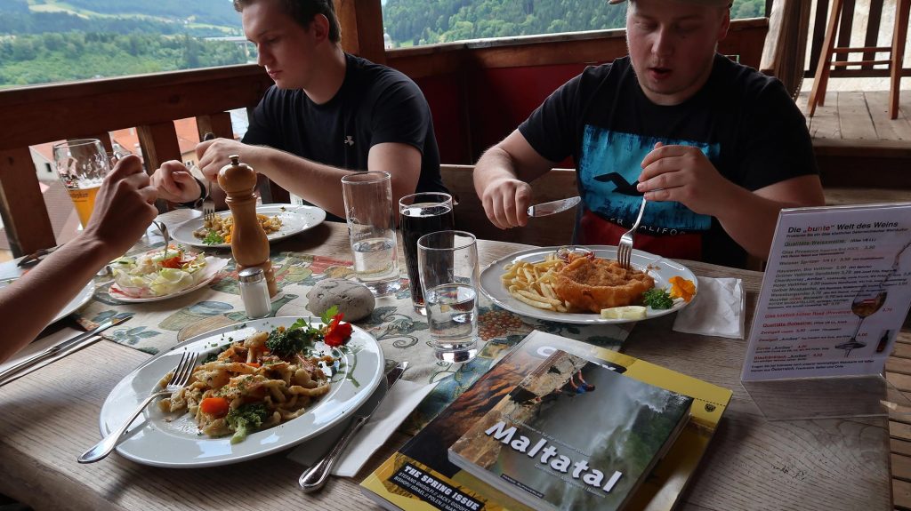 Das ild zeigt einen Esstisch mit Spätzle und Wiener Schnitzel und den Gästen auf der Alten Burg in Gmünd.