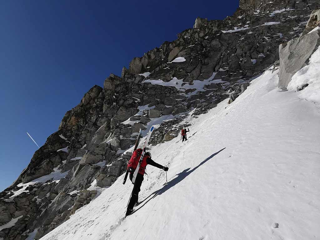 Das Bild zeigt zwei Skitourengeher in der Gössrinne an der Hochalmspitze. Sie steigen über die steile Rinne auf, links im Hintergrund ein felsiger Granitgrat.